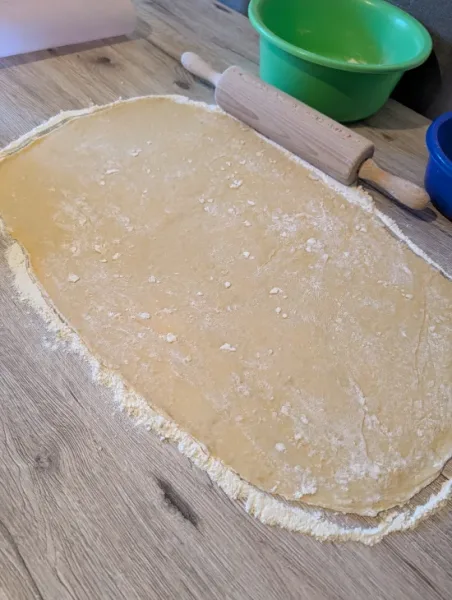 Ausgerollter Dinkel-Hefeteig als Rechteck auf einer bemehlten Holzfläche