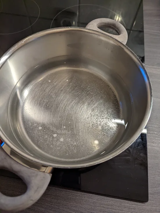 Topf mit Wasser auf dem Ceranfeld, das gerade zu sieden beginnt