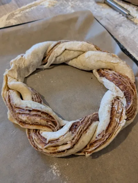 Der geflochtene Zopf liegt als geschlossener Kranz auf dem Backpapier