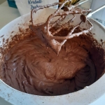 Schokoladen-Teig in einer weißen Schüssel mit einem Mixer-Rührwerkzeug, daneben eine Tüte mit der Aufschrift